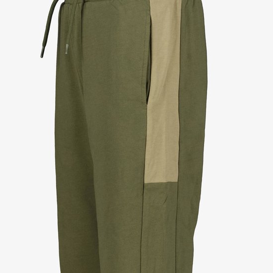 Close-up van de olijfgroene joggingbroek, tonend het beige zijpaneel, de steekzak en het trekkoord.