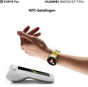 Hand met Huawei Watch GT 7 Pro met geel bandje, dichtbij een betaalautomaat.