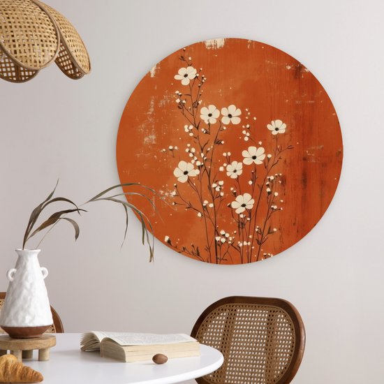 Cercle mural rond avec des fleurs blanches sur fond rouille, suspendu au-dessus d'une table.