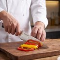Handen snijden rode en gele paprika met een Hi Nature koksmes met Damastpatroon lemmet.