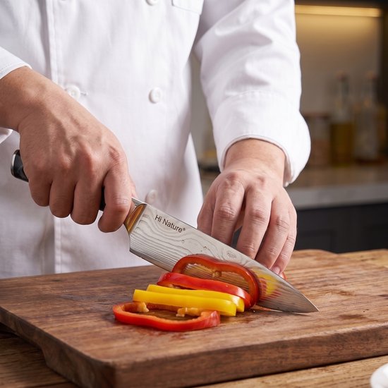 Handen snijden rode en gele paprika met een Hi Nature koksmes met Damastpatroon lemmet.