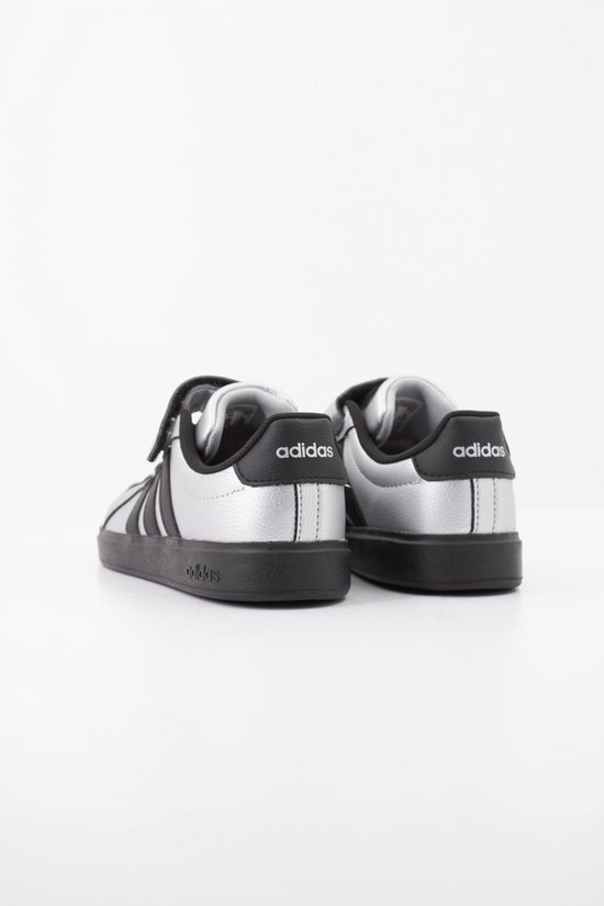 Achterkant van twee zilverkleurige sneakers met zwarte Adidas logo's op de hiel.