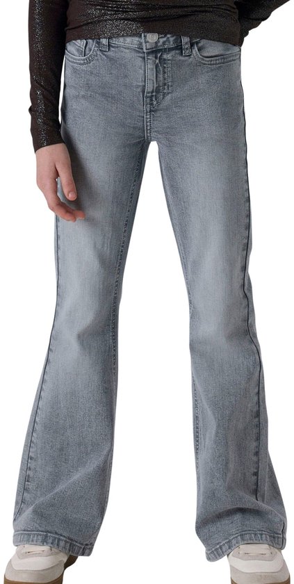Meisje in grijze bootcut jeans en glinsterende bruine top.