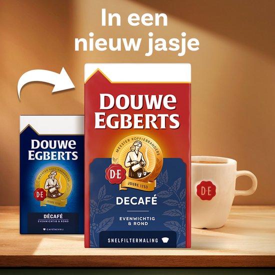 Twee verpakkingen Douwe Egberts Decafé koffie op een houten ondergrond. Een witte mok met DE-logo staat ernaast. Pijltje wijst naar nieuwe verpakking.