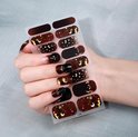 Bruine nagelstickers met manen, sterren en sterrenstof, met zwarte en gouden glitter.