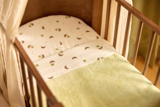Wiegje met een crème molton met bruine manen en groene zonnetjes, en een groen dekentje.