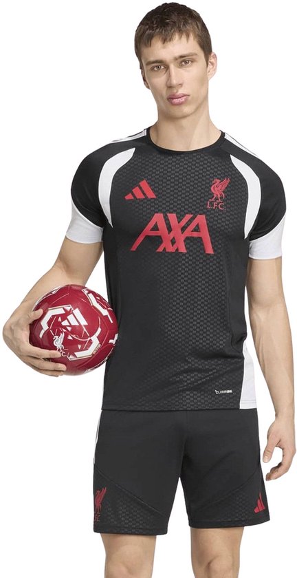 Man met zwarte Liverpool trainingstop met rode AXA-logo's en witte accenten, houdt een rode voetbal vast.