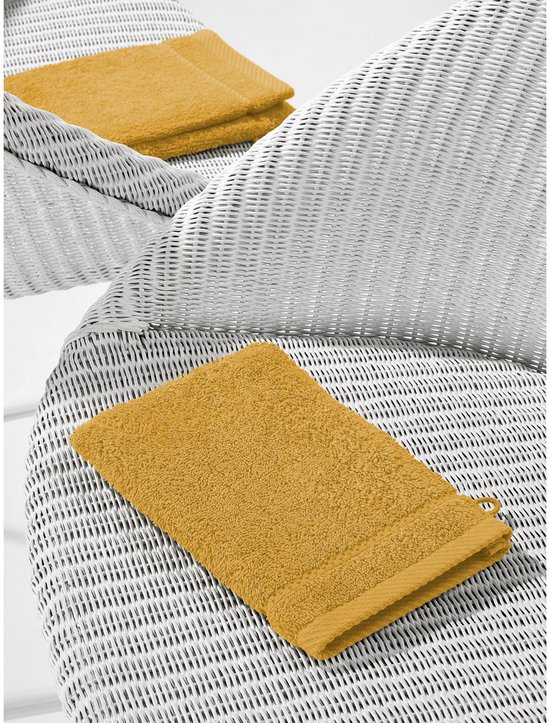 Gele washandjes op een witte stoel, een op de voorgrond, twee op de achtergrond.