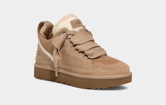 Beige UGG sneaker met dikke bruine plateauzool, bont voering en gevlochten veters.