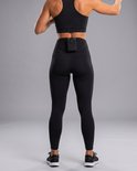 Vrouw in zwarte legging en sporttop, met microfoonriem en opbergvak, van achteren.
