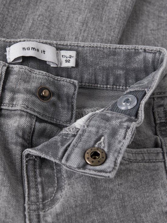 Sluiting met knopen en drukknoop van een grijze jeans, met maatlabel '1½-2Y 92'.