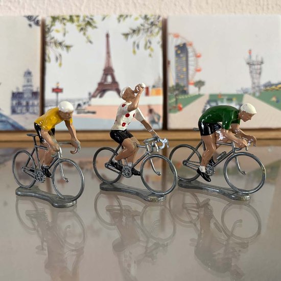 Trois figurines de cyclistes : jaune, blanc à pois rouges et vert, fond avec Tour Eiffel et grande roue.