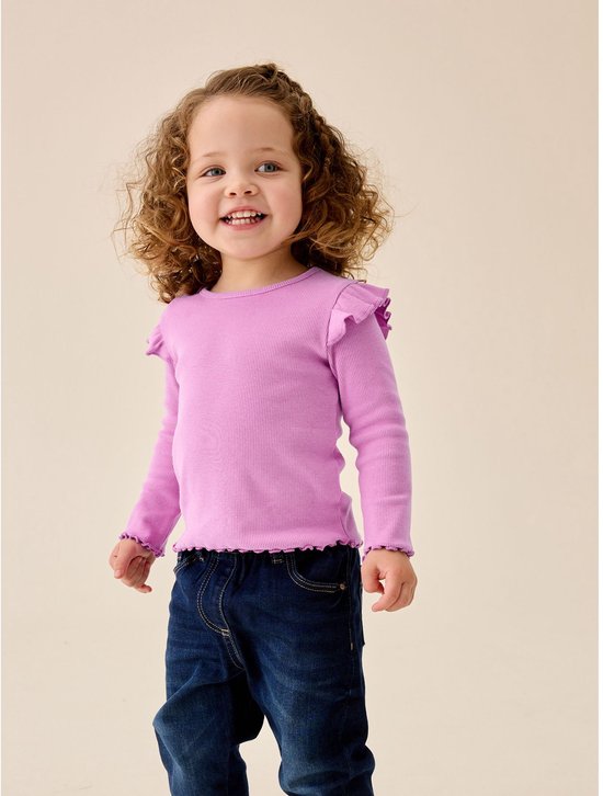 Lachend meisje met krullend haar in een paars shirt met ruches op de schouders en gegolfde zoom.