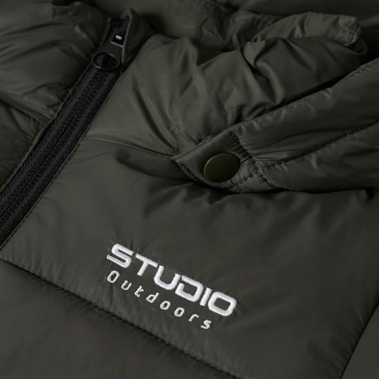 Detail van een donkergroene jas met de tekst "STUDIO Outdoors" geborduurd op de linkerborst.
