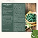 Verpakking met informatie over Chlorella Tablets 500 mg. Een houten lepel met groene Chlorella tabletten.