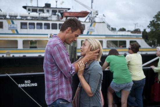 Een man met een paars geruite blouse die de kin van een vrouw aanraakt terwijl ze elkaar aankijken voor een boot.