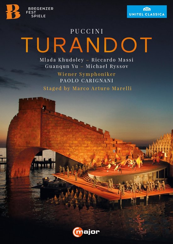 De poster van Puccini's Turandot op het Bregenz Festival toont een indrukwekkende podiumopstelling met een grote muur en trappen, met uitvoerenden in kostuums bij zonsondergang.