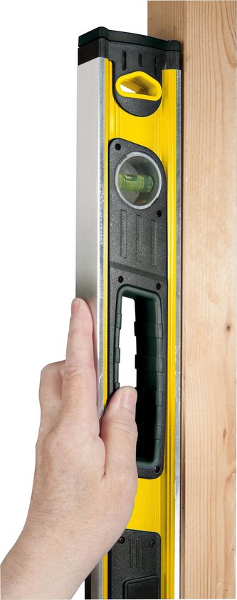 Hand gebruikt een verticale gele Stanley FatMax waterpas tegen een houten paal.