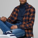 Man met geruite blouse over donkerblauwe coltrui