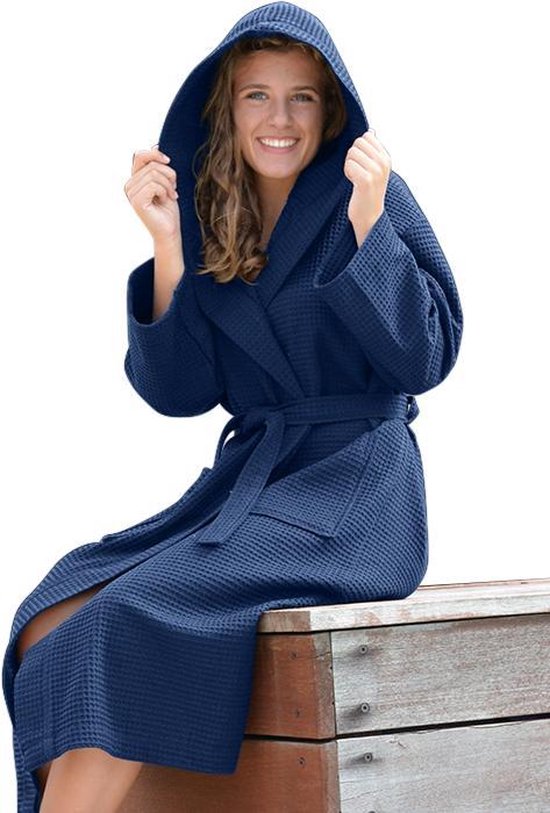 Femme sur un banc en bois en peignoir gaufré bleu foncé à capuche et ceinture.