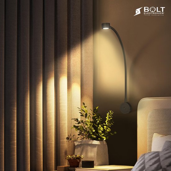 Lampe de lecture noire flexible illuminant une chambre à côté d'un lit avec des rideaux et une plante.