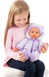 Een meisje met lang blond haar zit op een kruk en houdt een baby-pop in een paars, zacht pakje met capuchon vast.