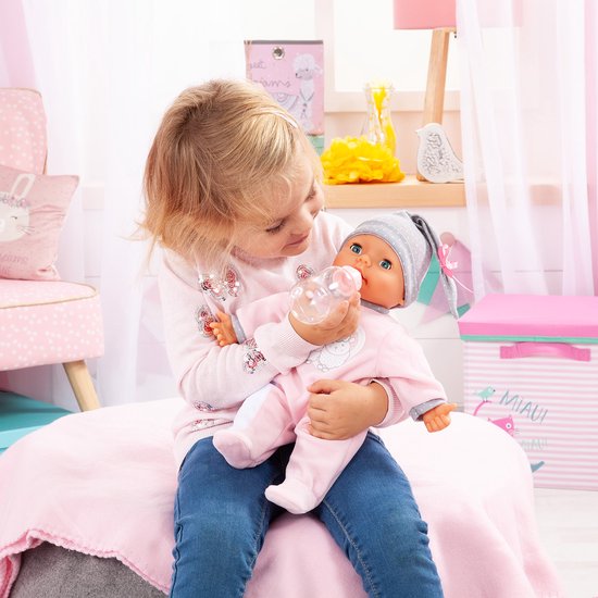 Meisje geeft een babypop met roze slaappakje en grijze muts een flesje.