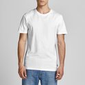 Man in een wit T-shirt en blauwe spijkerbroek, staand met een lichte draai.