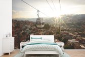 Behang - Fotobehang De zon gaat onder achter de Barrios kabelbaan bij Medellín in Colombia - Breedte 420 cm x hoogte 280 cm