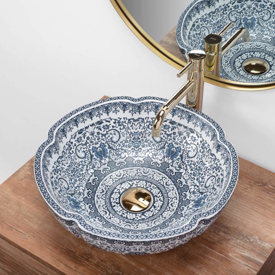Wastafel met bloemvormige rand en gedetailleerde blauw-witte patronen, met gouden kraan.