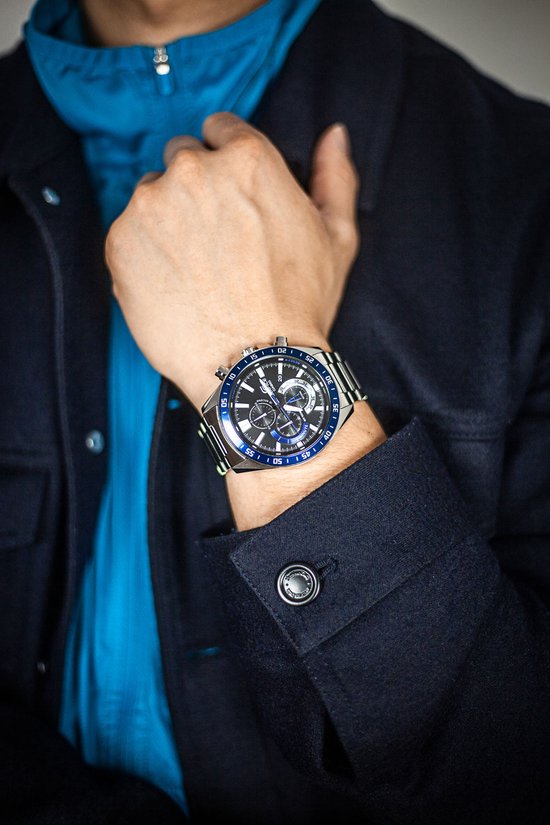 Herenhorloge met zilverkleurige band en zilverkleurige kast met blauwe accenten. Zwarte wijzerplaat met blauwe ring en chronograaf.