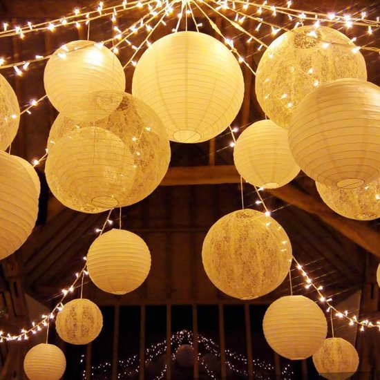 Witte lampionnen en slingers met lichtjes in een houten gebouw.