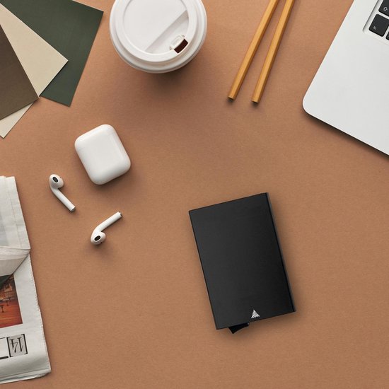 Porte-cartes noir sur fond brun avec ordinateur portable, écouteurs et tasse à café.