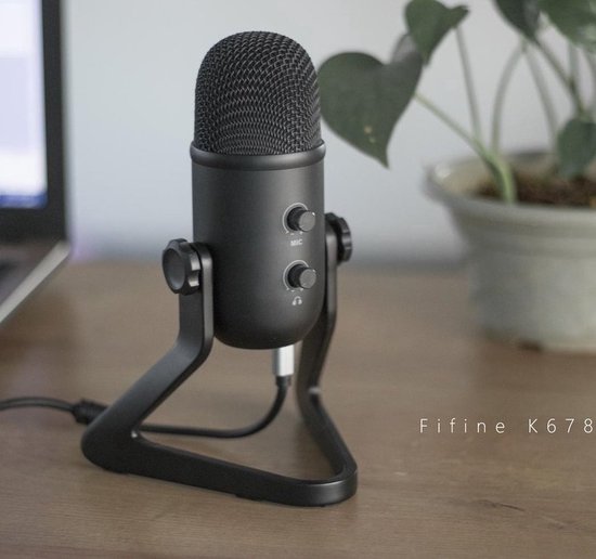 Zwarte Fifine K678 microfoon op een standaard met volumeknoppen, naast een laptop en plant.