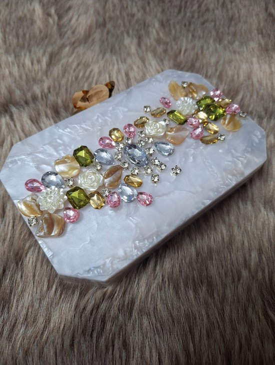 Details: Handmade resin clutch in a hexagonal shape embellished with gems and finished with a flower clasp. Comes with a golden sling. One chamber. No inner pocket. No side pocket. color white