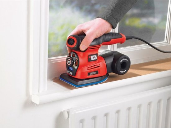 Een hand wordt gebruikt om een oranje en zwarte BLACK+DECKER multischuurmachine te gebruiken op een wit kozijn.