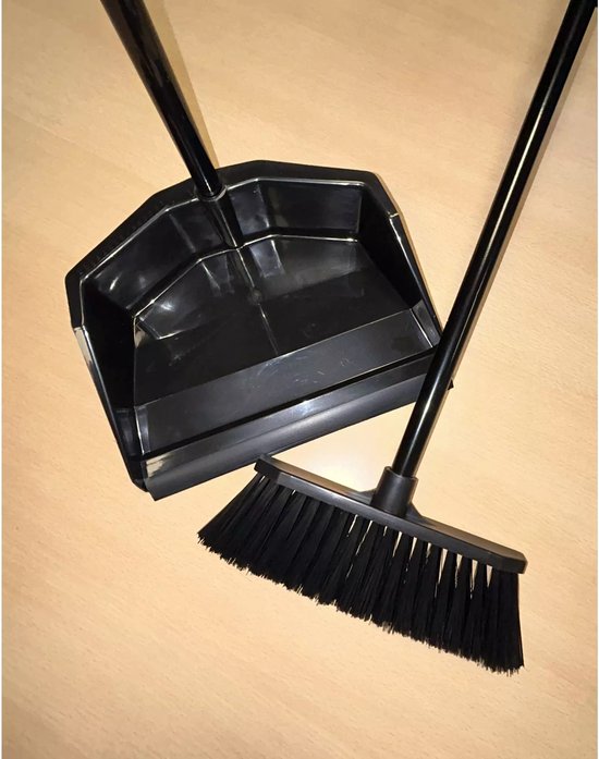 Zwarte stoffer en blik met lange steel, schuin op een houten achtergrond.