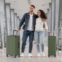 Man en vrouw, beiden met olijfgroene koffers, lopen door een moderne gang.