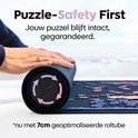 Handen rollen een puzzelmat op met een afbeelding van pijlen en de tekst 'Puzzle-Safety First'.