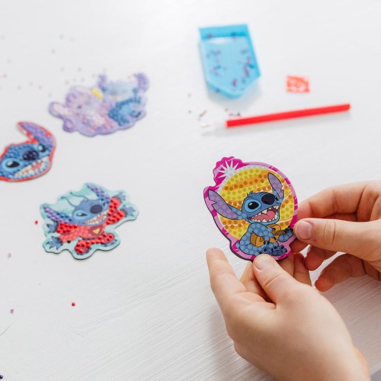 Mains d'enfants tenant une peinture diamant terminée de Stitch.