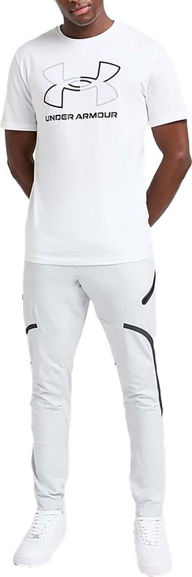 Man draagt wit Under Armour T-shirt met grijs/zwart logo en witte sportbroek.