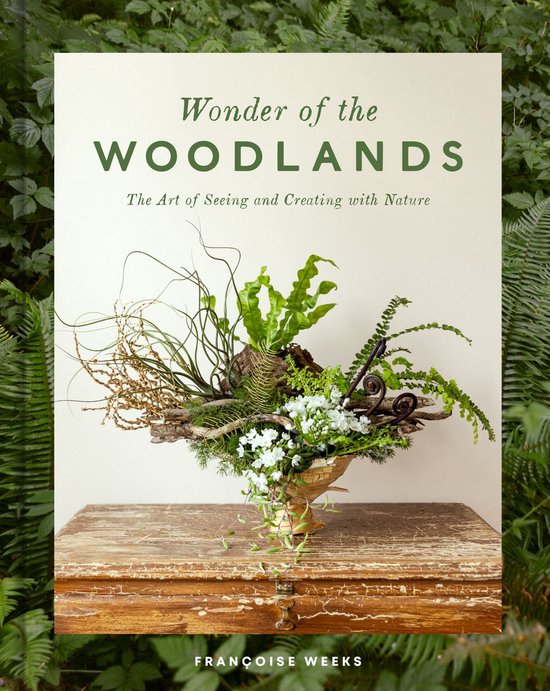 Livre 'Wonder of the Woodlands' avec un arrangement décoratif de verdure, branches et fleurs blanches.