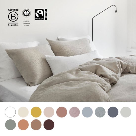 Opgebed en gestyled bed met beige linnen dekbedden en kussens, met keurmerken en kleuropties.