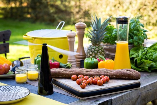 Zwarte ShooAway vliegenverjager naast vers brood, groenten en fruit op een houten buitentafel.