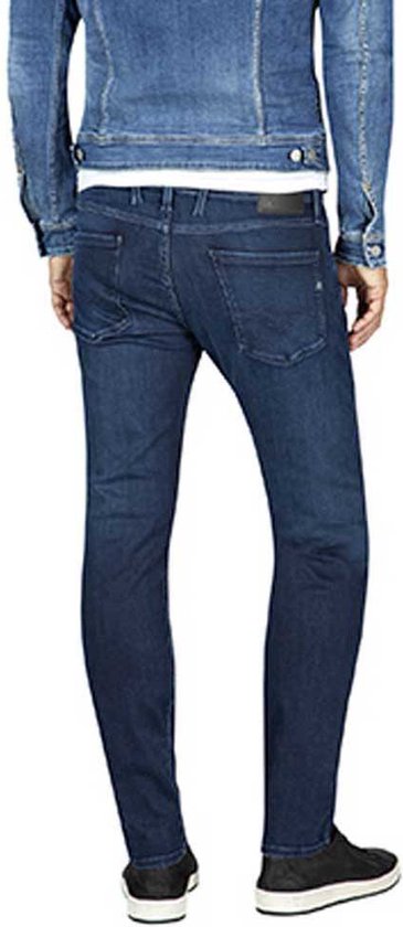 Man met donkerblauwe jeans en spijkerjasje, gezien vanaf de achterkant.