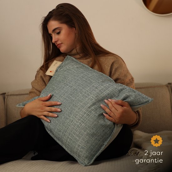 Vrouw met bruine trui omhelst lichtblauw Pleafs kussen. 2 jaar garantie.
