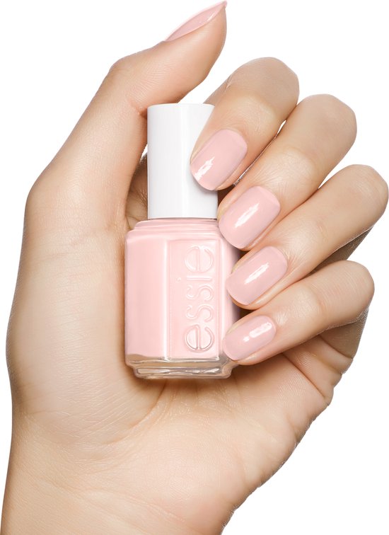 Hand met lichtroze Essie nagellak, houdt een flesje Essie nagellak vast.