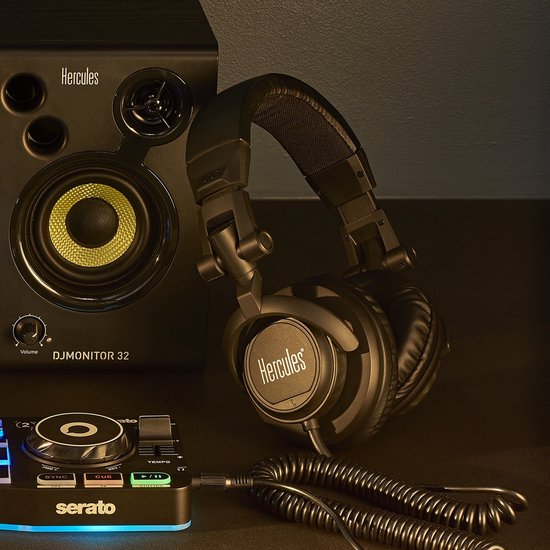Zwarte DJ-koptelefoon met Hercules-logo, naast een DJ-monitor luidspreker en mixer.