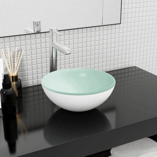 Lavabo blanc avec un bord supérieur en verre vert clair, sur un plan de travail noir.