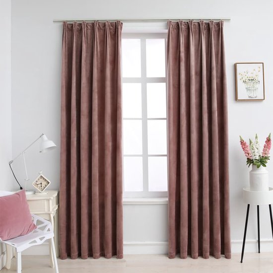 Roze fluwelen gordijnen voor een raam, naast een witte ladekast en een staande lamp.